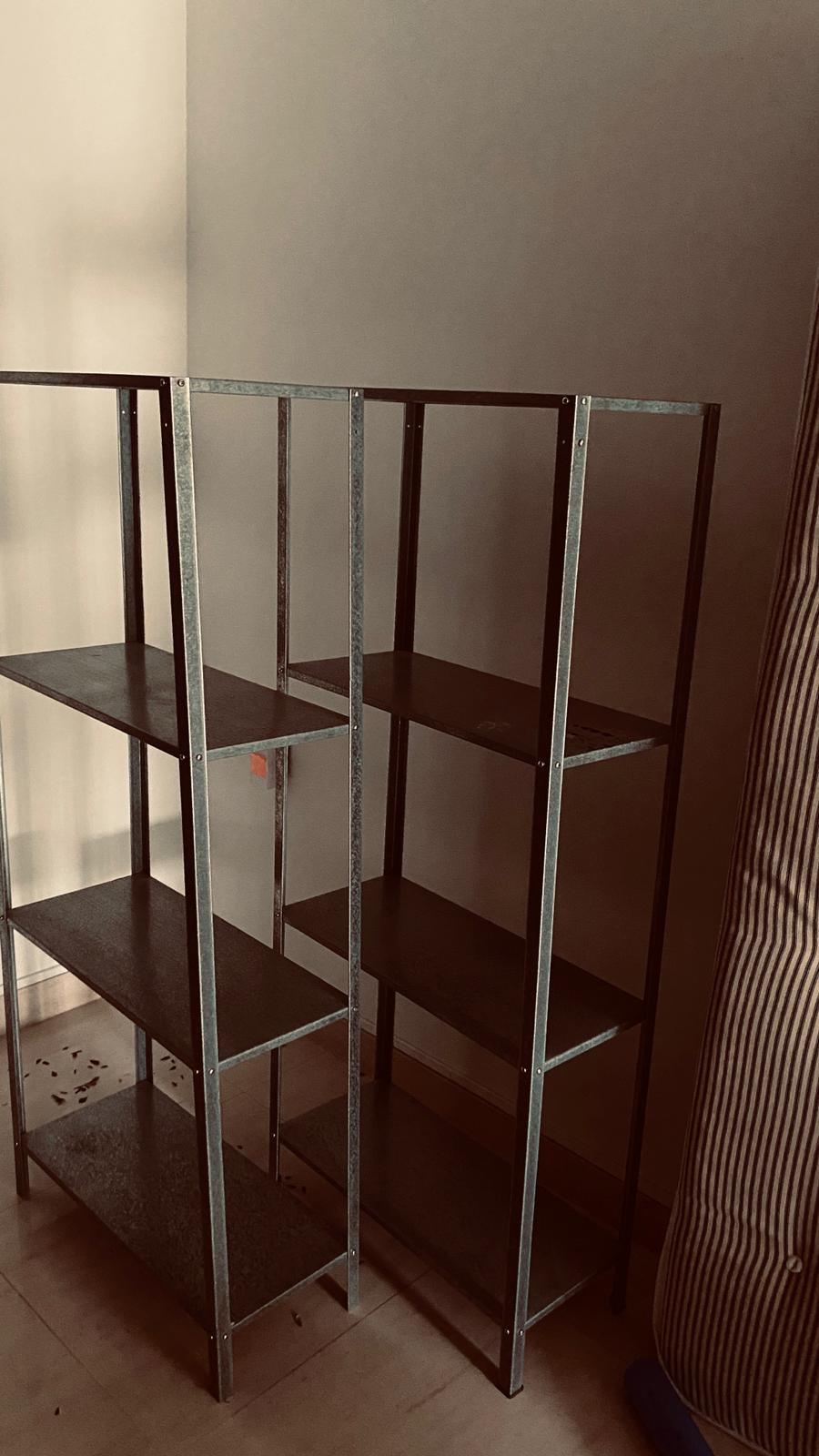 Two empty metal shelving units being removed from a residential room during a clearance.