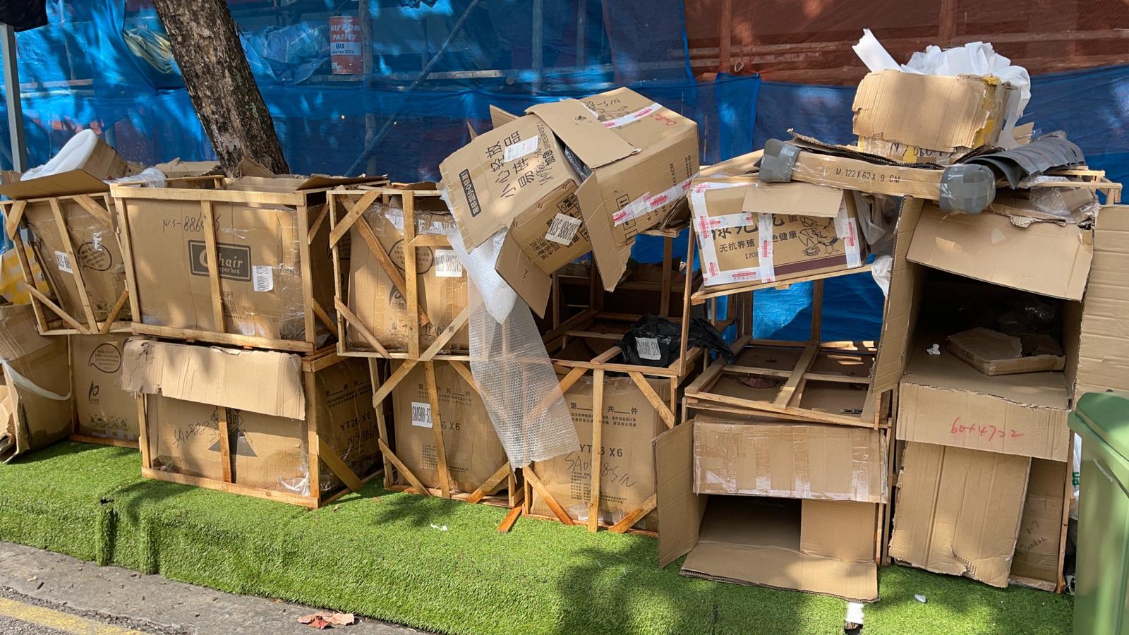 Stacked cardboard boxes and wooden crates piled on grass during a residential junk clearance.