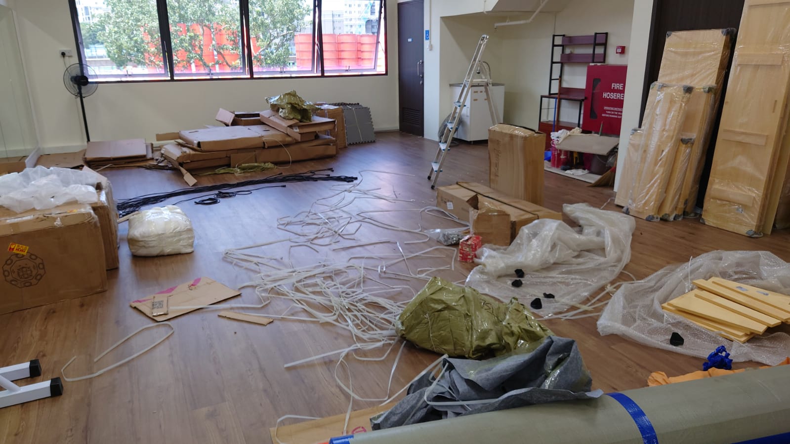 Cardboard boxes, packing materials, and tangled cables spread across a residential floor during a clearance.