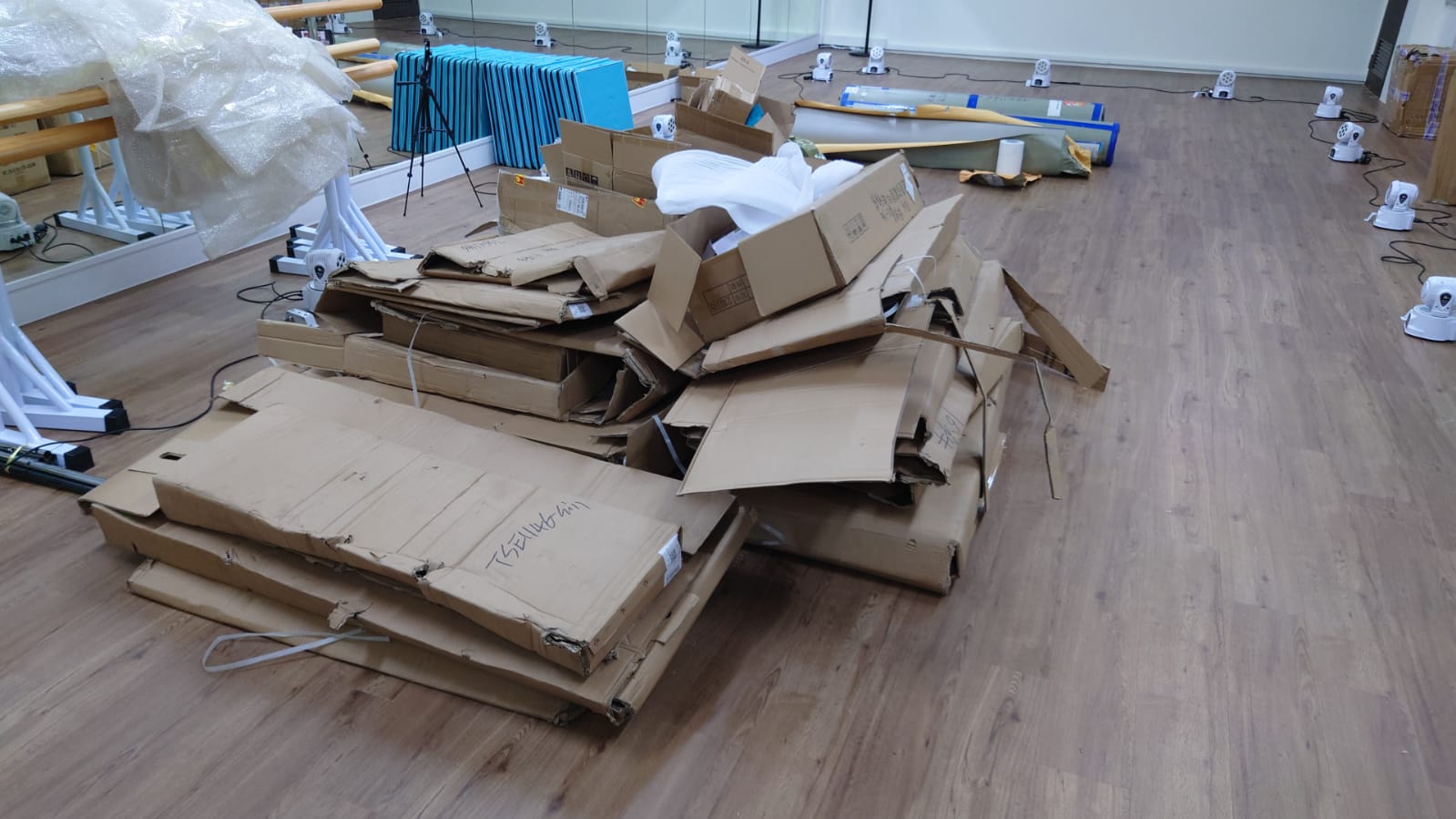 Stack of cardboard boxes with handwritten labels on a wooden floor, waiting to be removed.