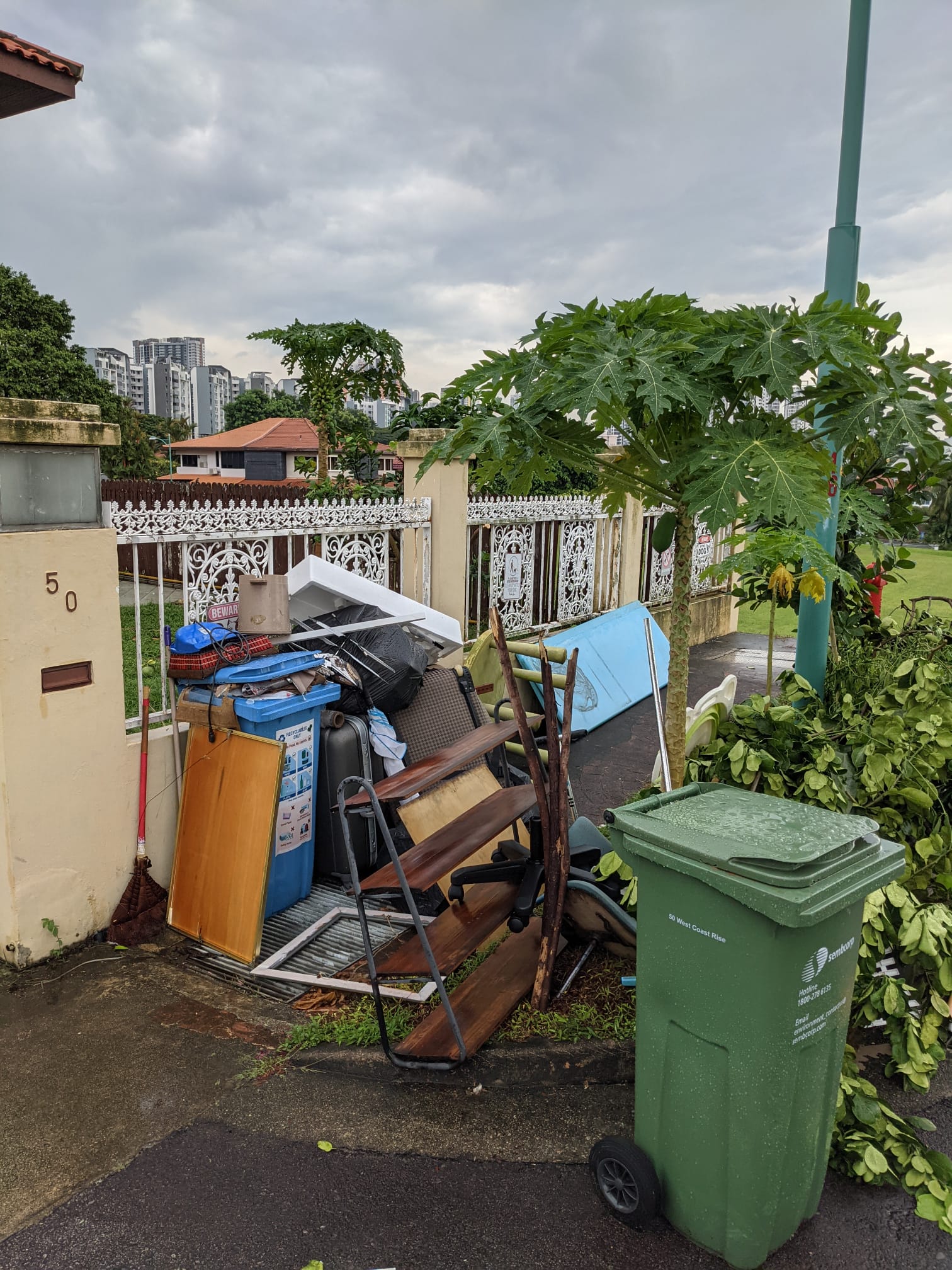 Pile of mixed household furniture and items stacked outside a residential property ready for collection.