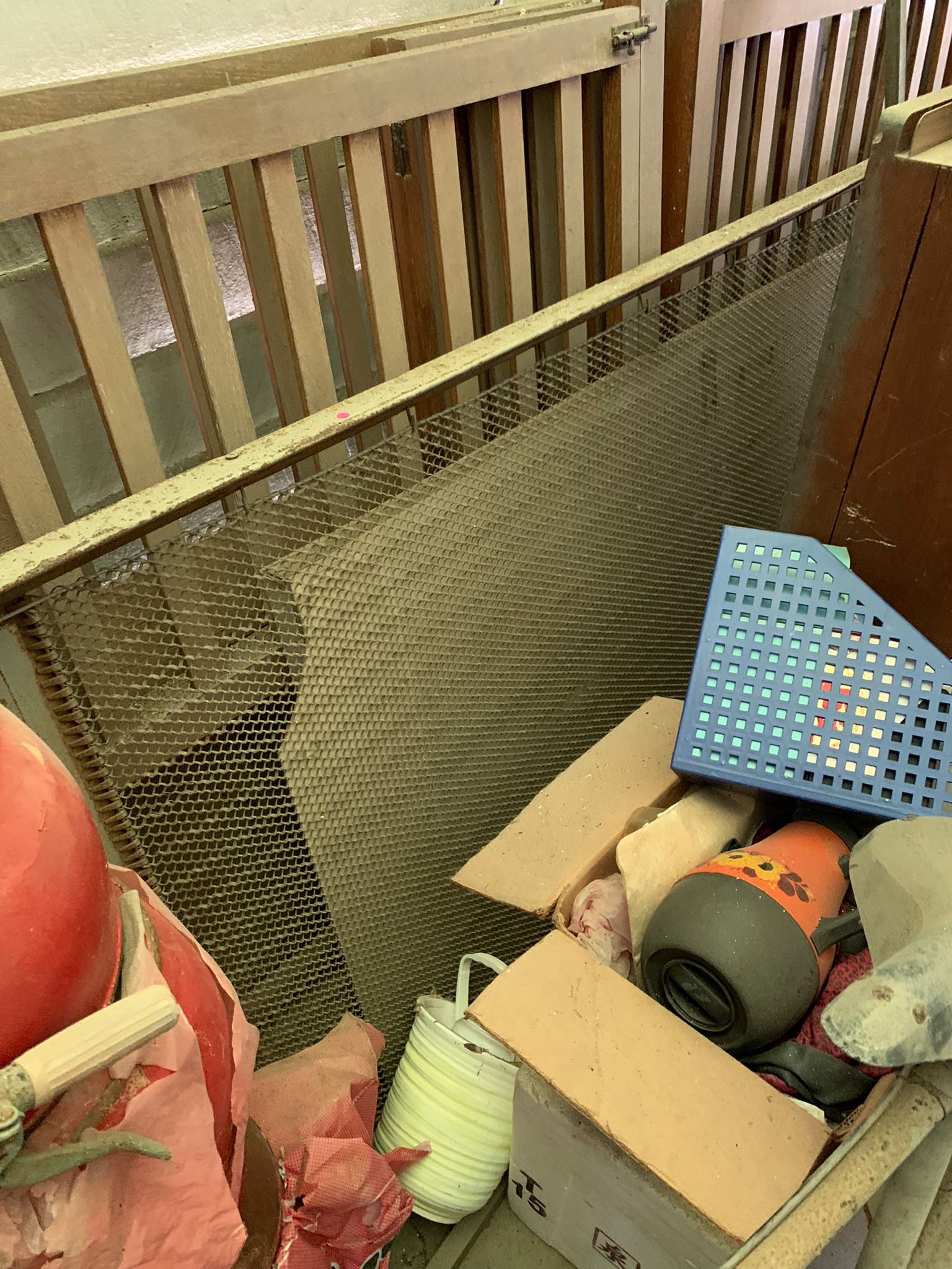Assorted household items including a red ball, orange thermos, blue plastic basket, and white containers stacked together for disposal.