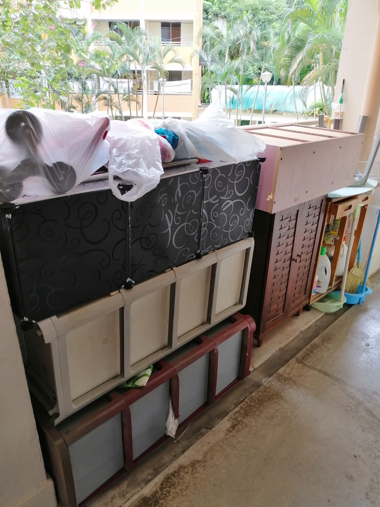 Stack of plastic storage cabinets with wrapped items and boxes piled on top in a residential space.