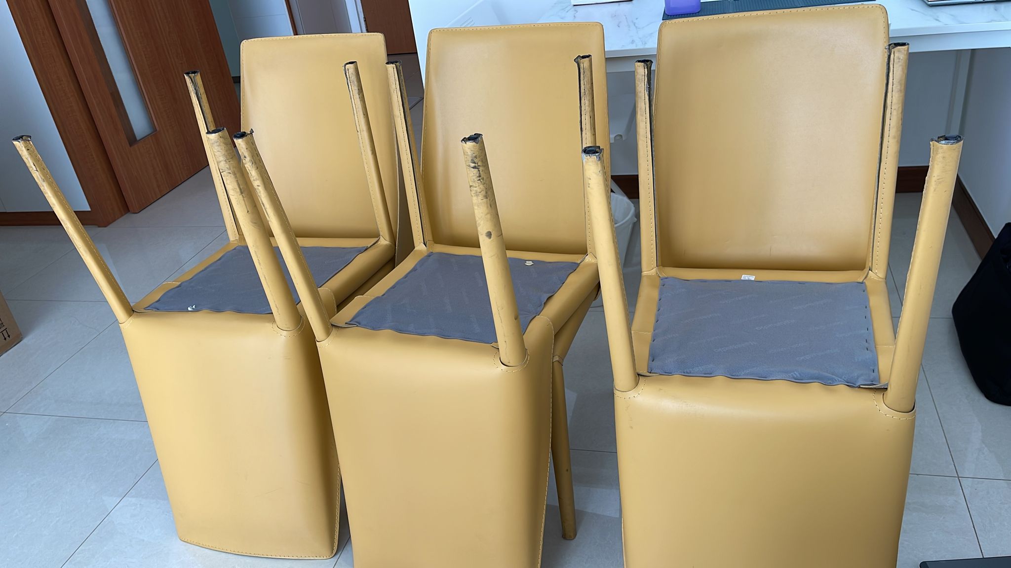 Stack of yellow upholstered office chairs with metal legs, ready for disposal.