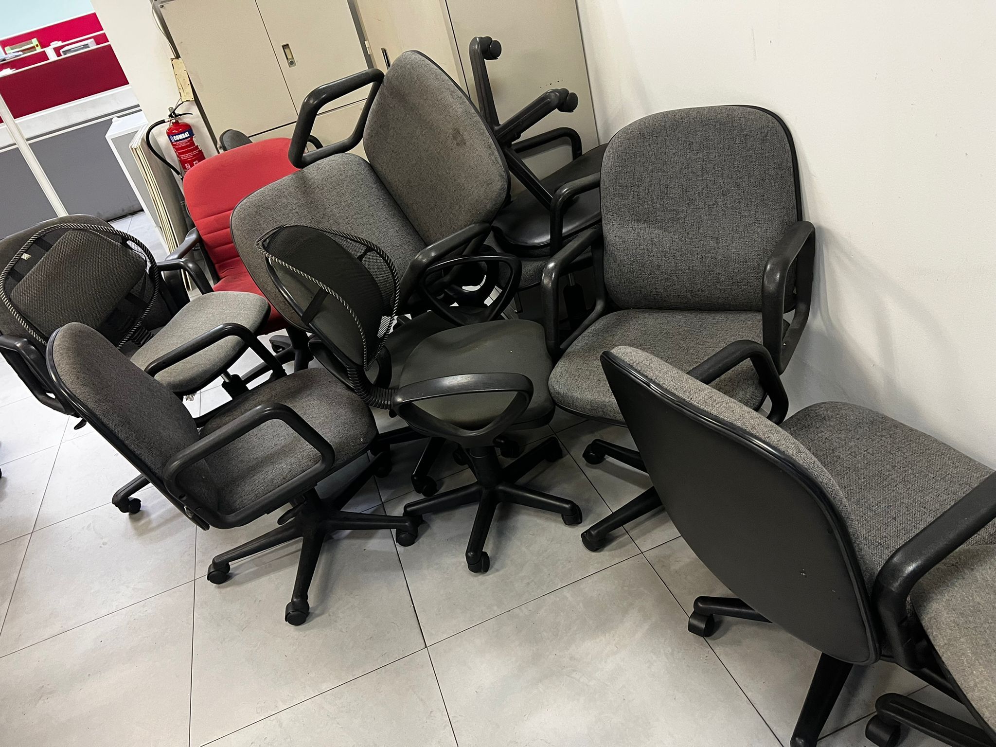 Stack of used office chairs piled in a commercial space, ready for disposal.