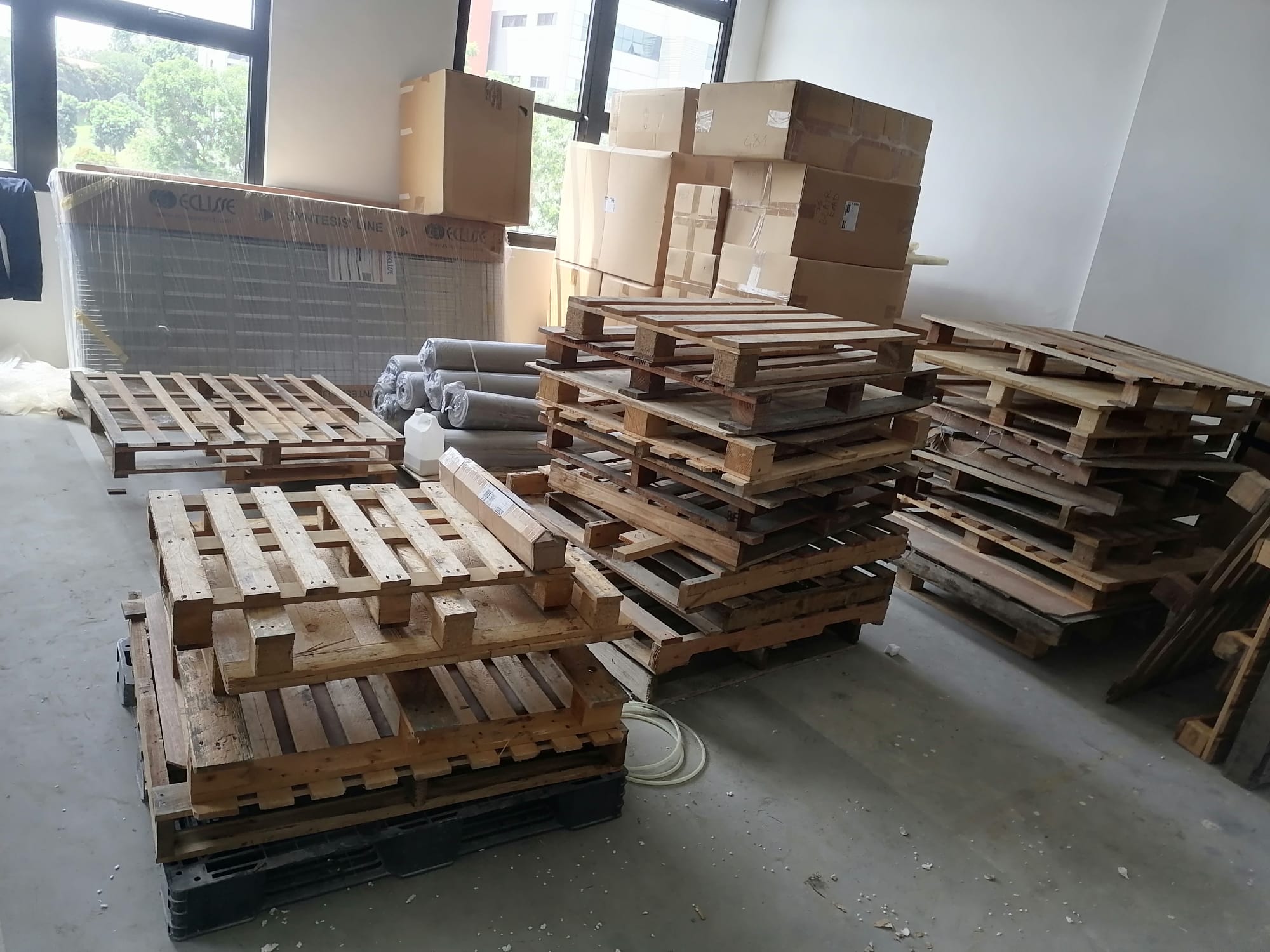 Stacked wooden pallets and flattened cardboard boxes arranged in a commercial storage space for collection.